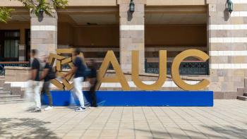 People walking next to the letters AUC