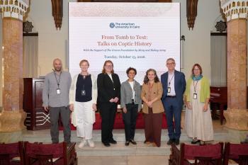A group of people smiling and standing in front of a banner with the title of the conference