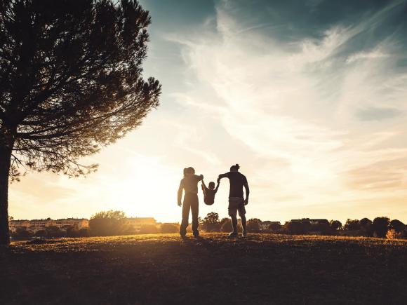 Silhouette of man, woman and child, and a tree representing public health in climate change