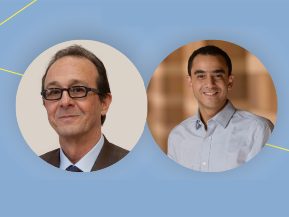 Two men smiling with light blue background