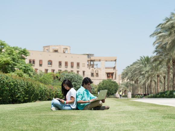 Boy and girl sitting back to back on grass