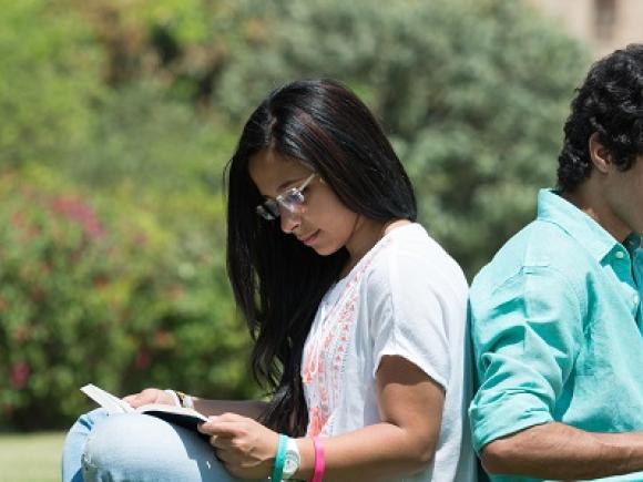 Girl and boy sitting back to back studying