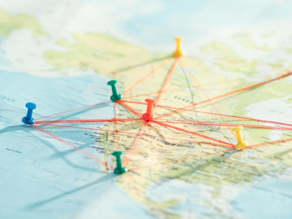 A picture of a paper map with multiple pins placed on it,