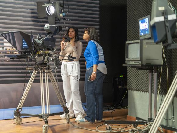 Two woman standing by a camera shooting an interview on AUC News