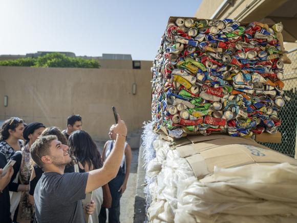Male student taking a photo of recycled cans