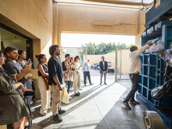 Instructor and students watching the operation of a machine recycling shredded paper