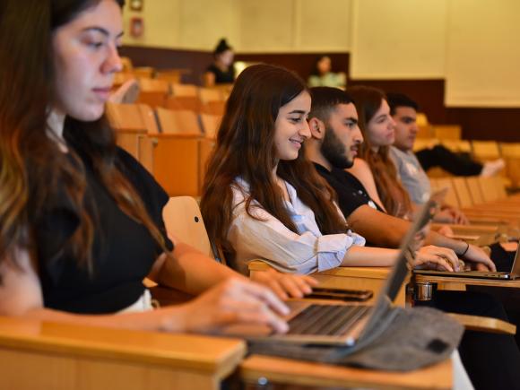 students sitting in a class with their laptop on the desk