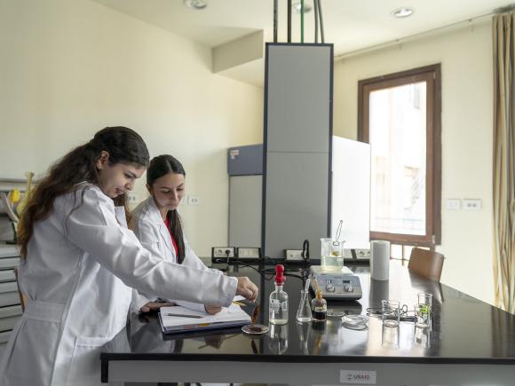 student wearing lab coats and working with chemicals