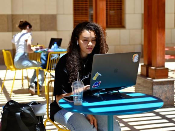Girl sitting on her laptop outdoors