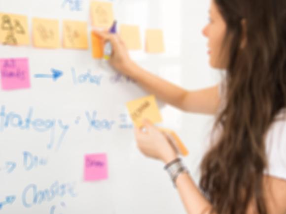 Girl putting a sticky note on white board