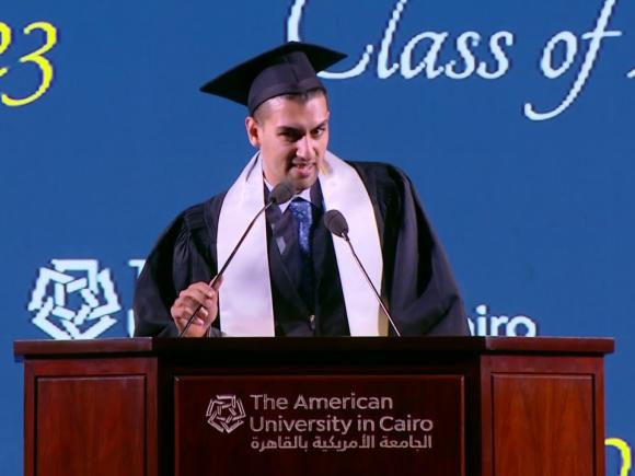 Male speaking at podium wearing his cap and gown