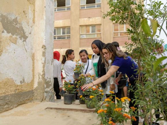 Students planting flowers at a school, as part of the collaboration between AUC and Ministry of Education