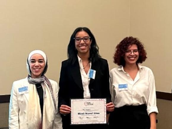 Three females standing next to each other and the one in the middle is holding a certificate