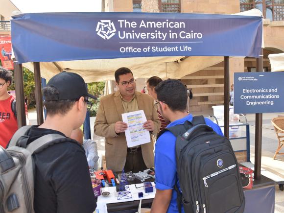 2 new students talking to professor about courses in Explore the Disciplines Fair at AUC