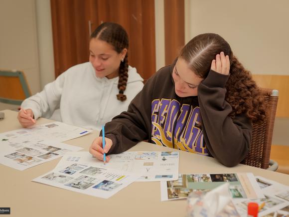 2 girls in class sketching with moodboards infront of them