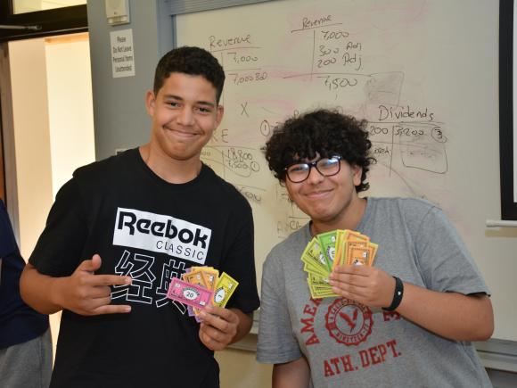 2 students in class holding monopoly cards