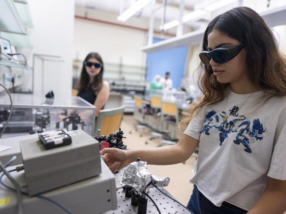 Two girls wearing black goggles in an experiment lab