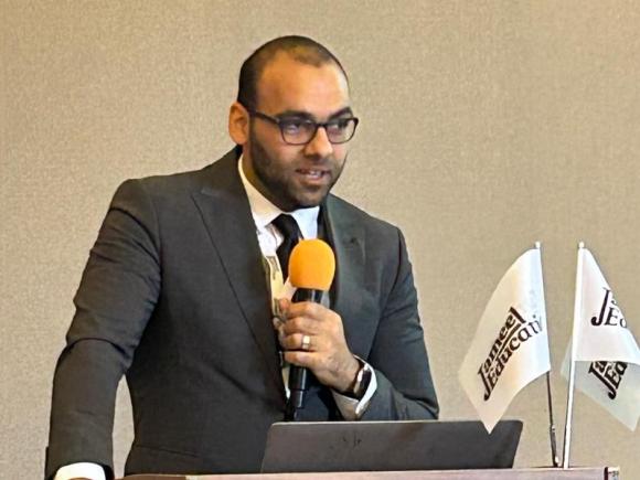 A male speaker holding a mic behind a podium