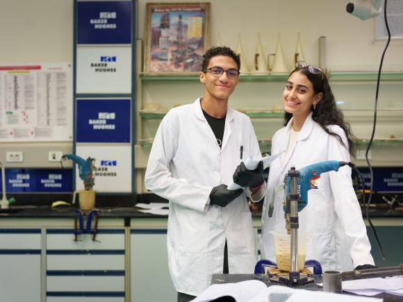 two girls wearing white coats in a lab room