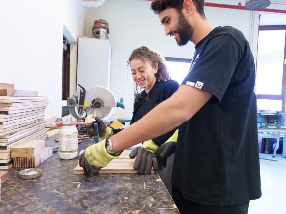 a girl and a boy wearing black tshirts working on an experiment in a lab