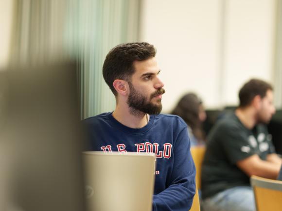 a student with long brown hair and long beard wearing a navy long sleeve tshirt