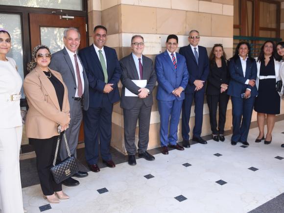 A group of women and men from AUC and Attijariwafa bank Egypt pose for a photo in front of a classroom
