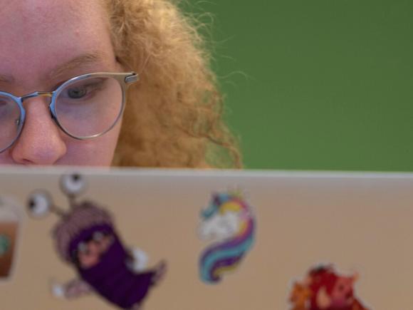 A girl with orange hair working on her laptop