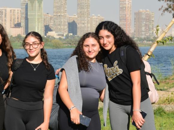 Four girls standing on grass and the Nile is behind them
