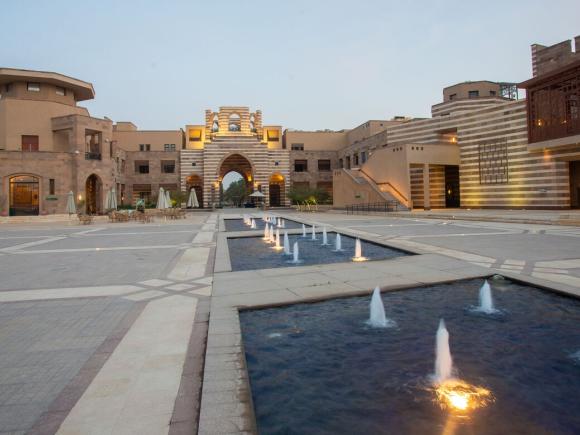 Open courtyard at AUC featuring fountains, stone buildings, and a large archway.