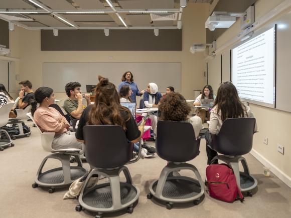 Students participate in a discussion-based class in a modern AUC smart classroom with projected materials.