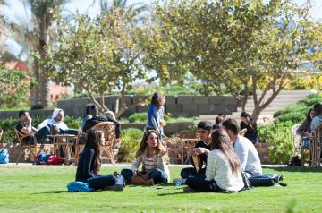 group of girls and boys sitting on grass in the garden