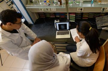 three students sitting infront of a laptop