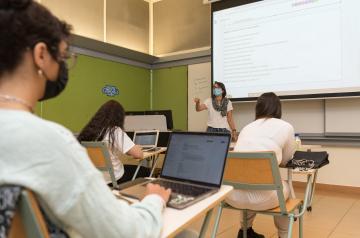 Students sitting in a classroom in front of a white board