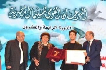 A woman handing an award to a student at 24th National Egyptian Film Festival