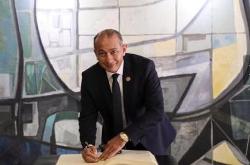 A man smiling and appears to be signing in a book