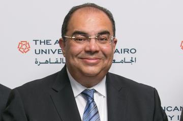 Man smiling wearing a suit and glasses