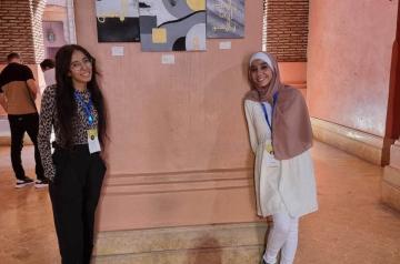 Two girls standing beside a wall with their project