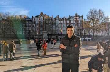Male student standing in front of an old building