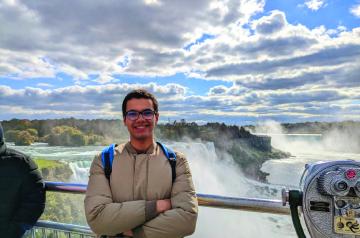 Male student standing in front of a waterfall