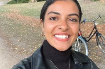 Female student smiling and standing in front of a bicycle
