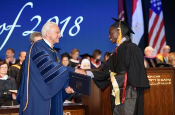 AUC President Francis Ricciardone shakes hands with a graduate student receiving his diploma