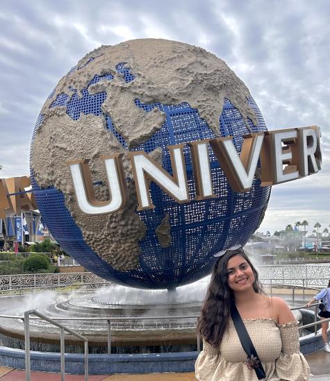 A female is standing in front of the a globe at Universal Studios