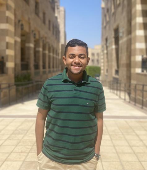 A male wearing a green and blue striped polo shirt