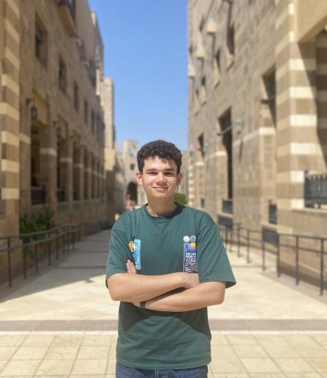 A male is standing crossing his arms and smiling