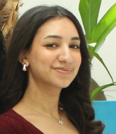 A girl with long black hair wearing maroon shirt