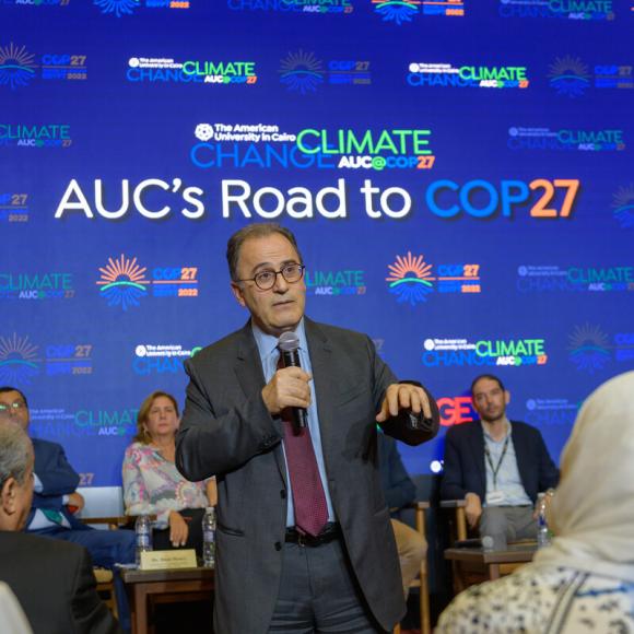 Man talking into a microphone to the audience AUC's Road to COP27
