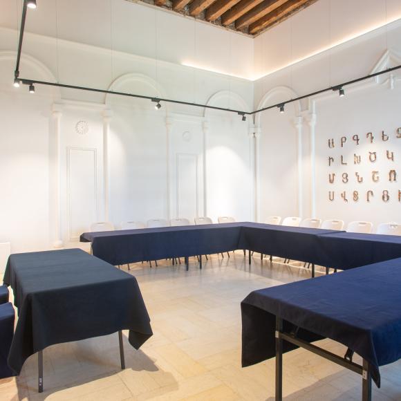 Chairs and tables in a room with Armenian letters on the wall