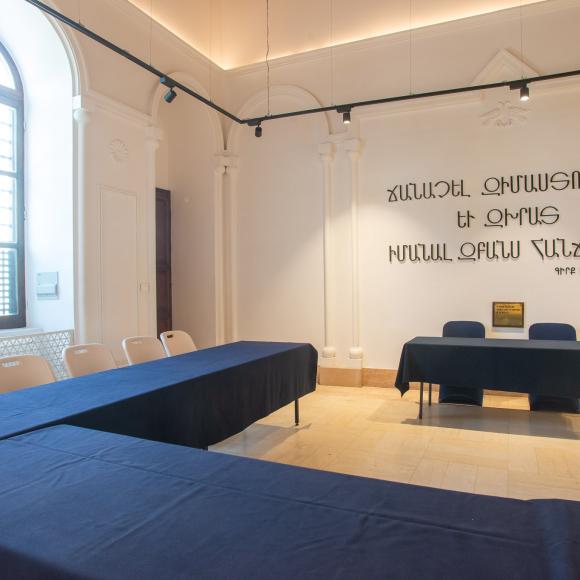 Chairs and tables in a room with Armenian text on the wall that reads To acquire wisdom and guidance, learn the knowledge of the intellect.