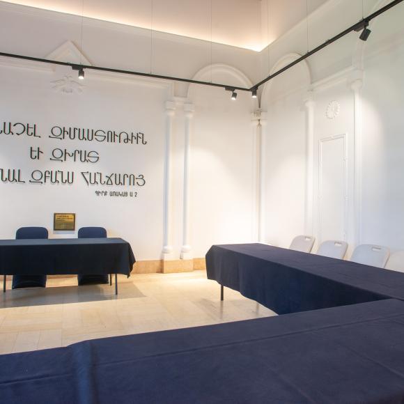 Chairs and tables in a room with Armenian text on the wall that reads To acquire wisdom and guidance, learn the knowledge of the intellect.