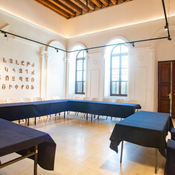 Chairs and tables in a room with Armenian letters on the wall